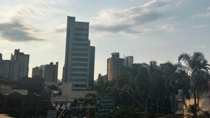 Vista urbana de Campinas com prédios comerciais, palmeiras, trânsito e céu parcialmente nublado.
