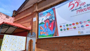 Fachada de prédio de tijolos com banner do 53º Salão Internacional de Piracicaba com ilustração colorida e lista de países em destaque, ao ar livre.