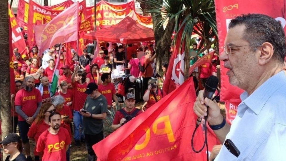 Rui Costa Pimenta discursa em ato do Partido da Causa Operária (PCO), diante de manifestantes com bandeiras vermelhas.