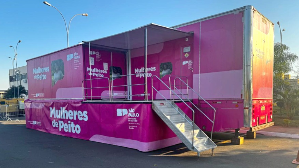 Ônibus adaptado com comunicação visual do projeto “Mulheres de Peito” e “São Paulo”, com rampa de acesso e estrutura estacionada em área externa ao entardecer.