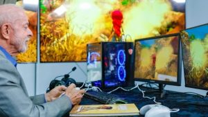Presidente Lula observa jogo digital em computadores e monitores durante visita a espaço de desenvolvimento de games.