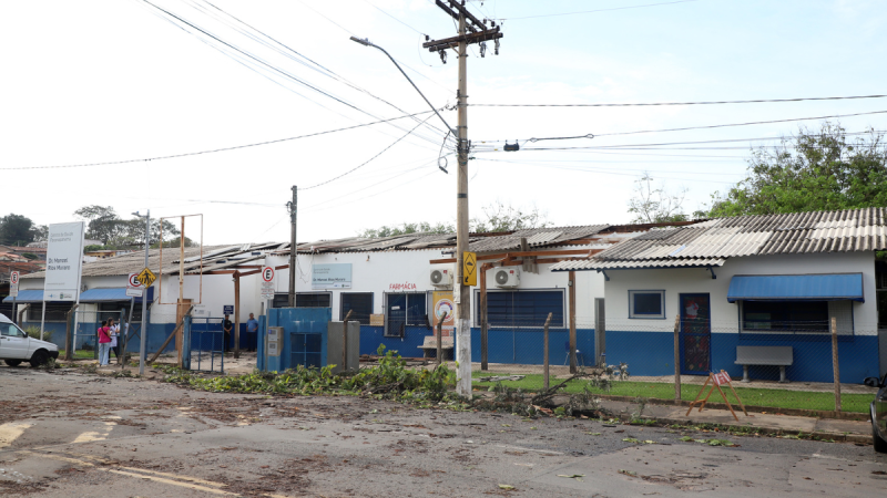 Vista externa CS Paranapanema simples com fachada pintada de azul e branco, cercas e portões, placas de identificação e postes de energia ao longo da rua, sob céu claro.
