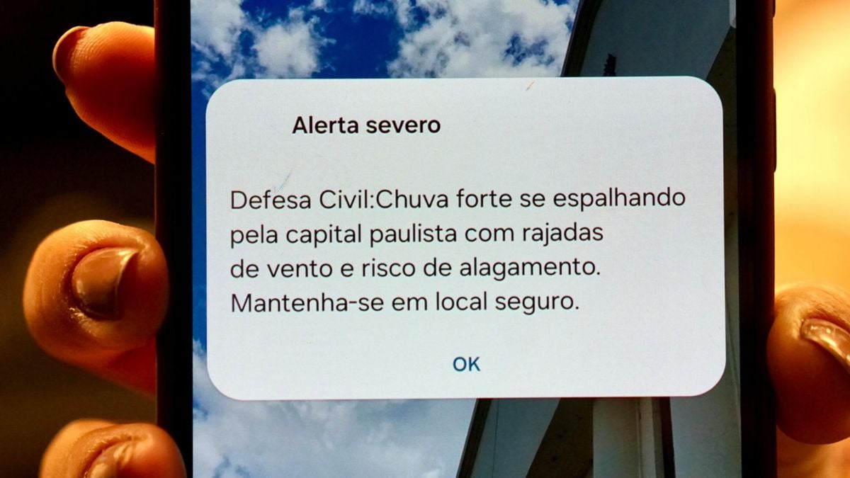 Celular mostrando alerta severo da Defesa Civil: Chuva forte se espalhando pela capital paulista, com rajadas de vento e risco de alagamento.