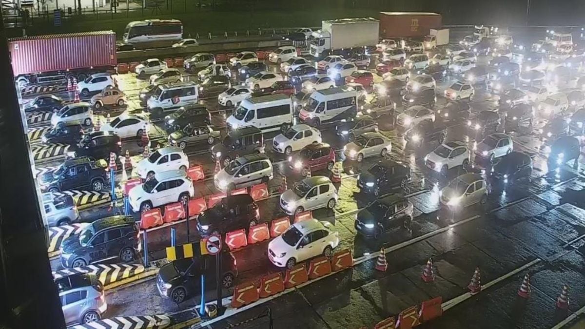 Vista ampla de um grande congestionamento na rodovia da Imigrantes movimentada, com muitos carros e caminhões parados em meio à sinalização e faixas de trânsito durante a noite.