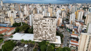 Vista aérea de Campinas com prédios altos, ruas movimentadas e área com árvores e jardins em primeiro plano, em um dia claro