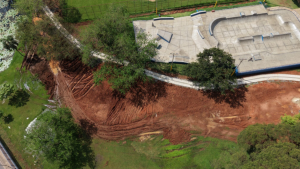 Vista aérea de obra da Área do Lazer em Piracicaba com grande movimentação de terra em área rural, mostrando escavação, drenagem e estruturas de concreto ao fundo.