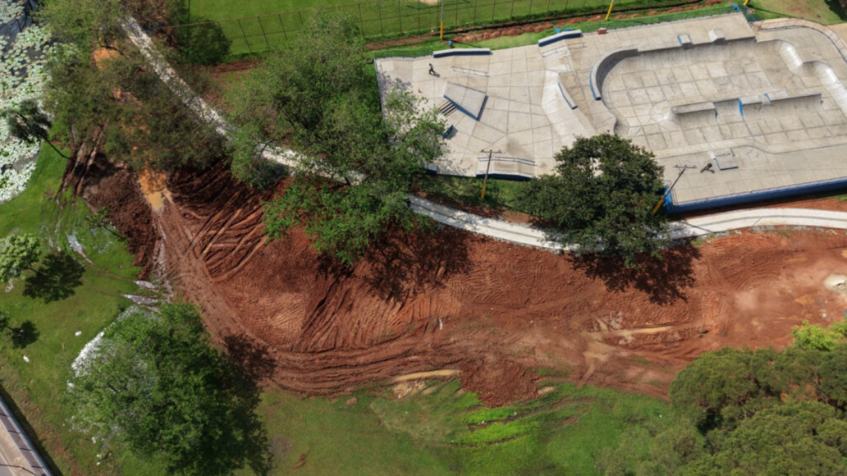 Vista aérea de obra da Área do Lazer em Piracicaba com grande movimentação de terra em área rural, mostrando escavação, drenagem e estruturas de concreto ao fundo.