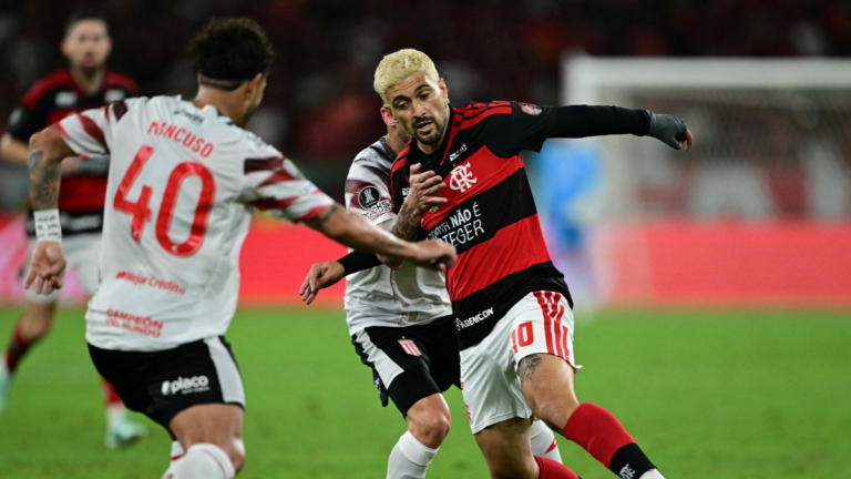 Arrascaeta, jogador do Flamengo, disputa jogada com jogadores do Estudiantes.