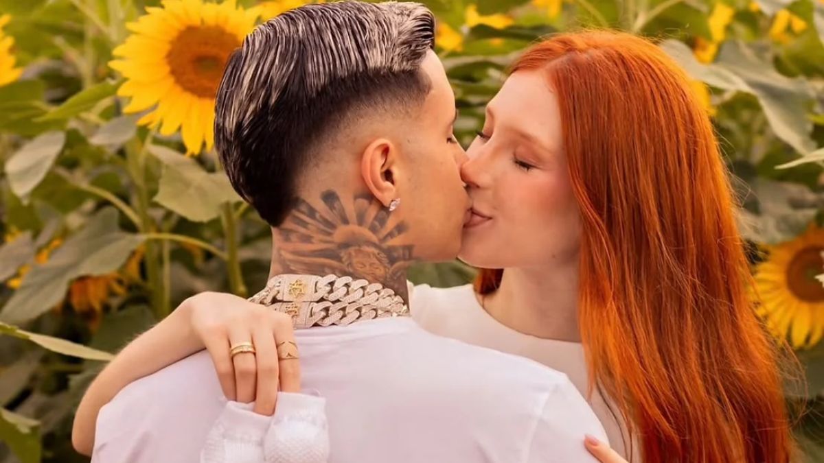 MC Paiva e Soso Careca apaixonado se beijando em um campo de girassóis, com flores amarelas ao fundo, clima romântico em ensaio fotográfico de outono