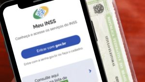 Celular com o aplicativo Meu INSS ao lado de um título de eleitor, em referência à biometria exigida em determinados pedidos de benefícios previdenciários.
