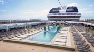 Uma piscina retangular de navio MSC de cruzeiro rodeada por fileiras de espreguiçadeiras vazias num deck de madeira.