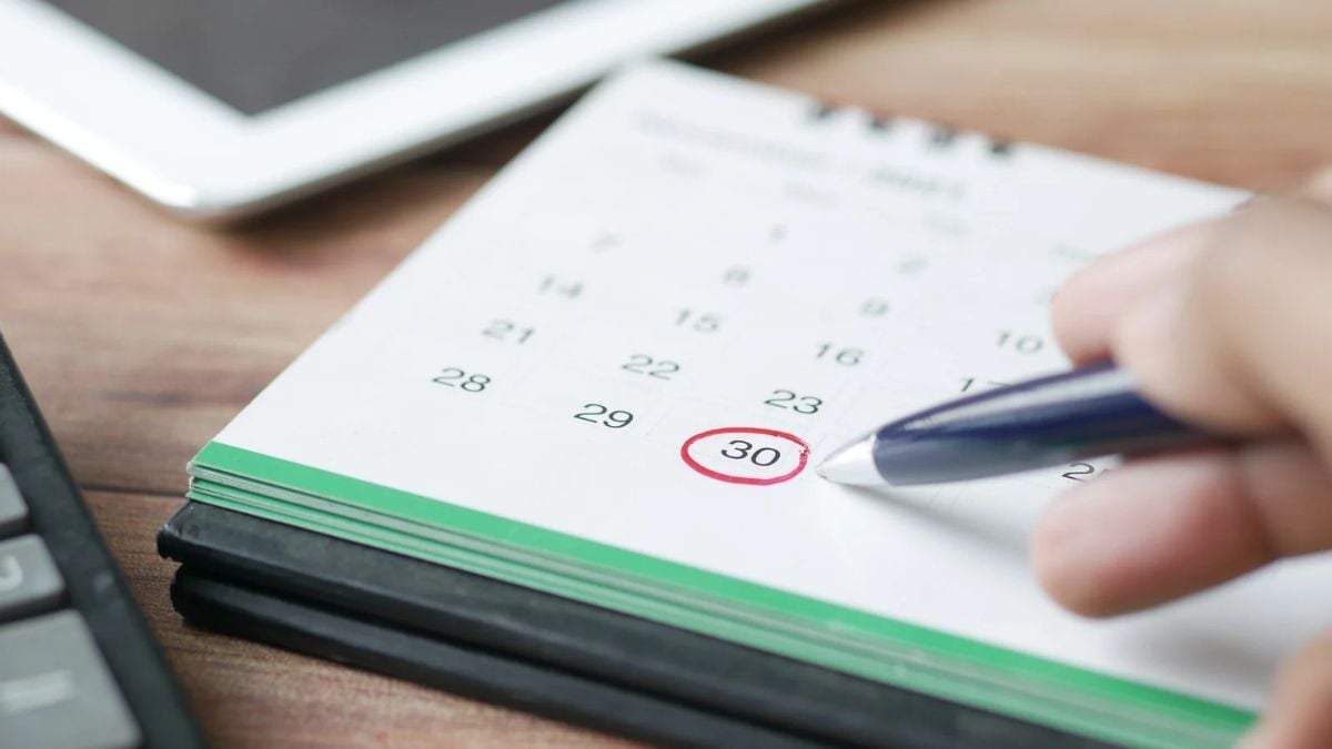Hoje é feriado: mão marcando o dia 30 em calendário no caderno com caneta, sugerindo possibilidade de emendar folgas a partir de uma sexta-feira.